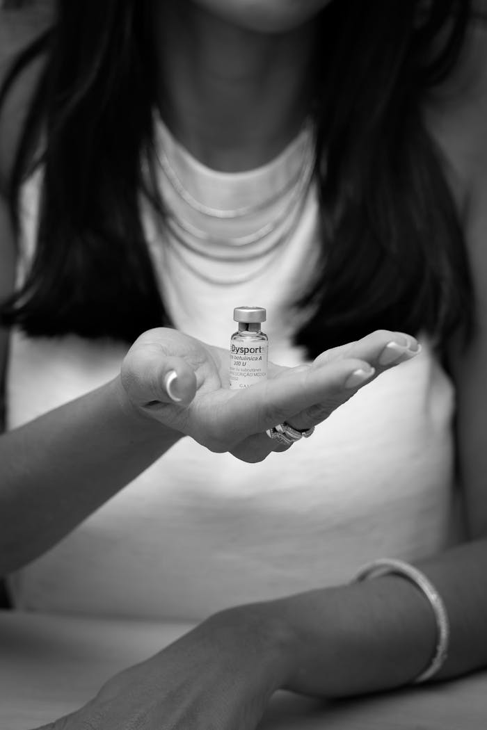 Black and white photo of woman holding a vial of cosmetic injection in her hand